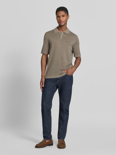 Męski model nosi Regular Fit Poloshirt aus reiner Baumwolle Marc O'Polo × DFB Travel Collection o efekcie: jednolity kolor, z wyhaftowanym logo, naszywką z logo, kołnierzykiem polo, zapięciem na 2 guziki, krótkim rękawem, wykończeniem materiału: dzianina, bawełna; cała sylwetka z przodu