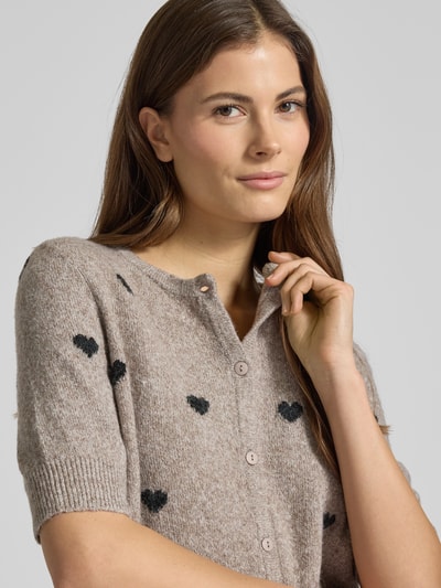 Frauenmodel trägt Slim Fit Strickjacke mit Intarsien Modell 'DOFFY INTARSIA' von Vero Moda, Allover-Muster, floral, Nahaufnahme Oberkörper.