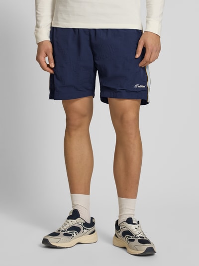 Männermodel trägt Shorts mit Label-Stitching Modell 'Slipstream' von PROHIBITED in Dunkelblau, Regular Fit, elastischer Bund, Ganzkörperansicht von vorne.
