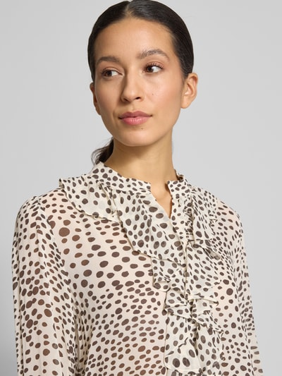 Kobiece modelka nosi bluzkę Relaxed Fit Bluse aus reiner Viskose Modell 'Canapa' od Marella, wiskoza, obszycie falbanami, długi rękaw, stójka, jasne tło, wzór w kropki, widok blisko górnej części ciała, ujęcie z przodu.