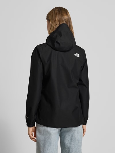 Kobiece model prezentuje Regular Fit Jacke mit Logo-Print od The North Face, czarny kolor, kaptur, długie rękawy, krój regular fit, długość tyłu w rozmiarze S: 68 cm, szerokość ramion w rozmiarze S: 37 cm, szerokość klatki piersiowej w rozmiarze S: 34 cm, długość rękawa w rozmiarze S: 62 cm, widok całej sylwetki z tyłu.