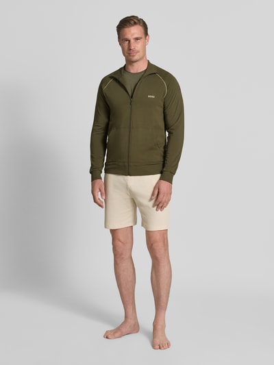 Męski model nosi Regular Fit Sweatjacke aus Baumwoll-Mix od BOSS w kolorze oliwkowym, gładka tekstura, Ganzkörperansicht von vorne.
