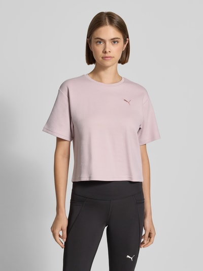 Frauenmodel trägt Relaxed Fit T-Shirt aus Häkelspitze von PUMA in zartem Rosa und schwarze Leggings, Ganzkörperansicht von vorne, Damen T-Shirt von PUMA.