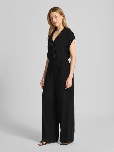 Kobiece modelka nosi czarny Jumpsuit aus Viskose mit V-Ausschnitt Modell 'MARRAKECH' od ICHI, czysta wiskoza, krój slim fit, długość całkowita 146 cm, szerokość w rozmiarze S 43 cm, przód, zdjęcie całej sylwetki.