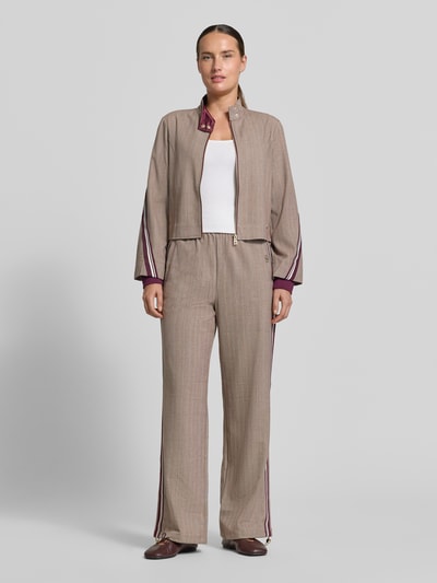 Vrouwenmodel draagt Wide Fit broek met viscose van Liu Jo, elastische materiaalmix, logodetail, tunnelkoord, steekzakken, bandwijdte maat S 38 cm, binnenbeenlengte 80 cm, rustig bruin met paarse accenten, ganzicht voorkant.