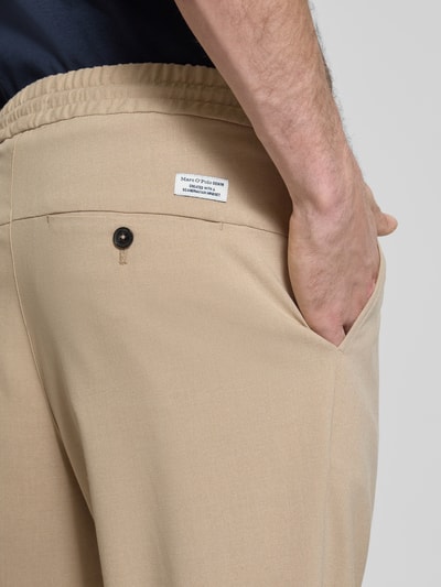 Männermodel trägt Spodnie z zakładkami w pasie Relaxed Fit Bundfaltenhose mit Viskose-Anteil Modell 'VIGGO CROPPED' von Marc O'Polo Denim, efekt: jednolity kolor, krój relaxed fit, średni stan, długość krótki, aplikacja: wyhaftowane logo, detal: zakładka w pasie, tunel, elastyczny ściągacz, boczne wpuszczane kieszenie, kieszenie z tyłu, mieszanka materiałów z dodatkiem wiskozy, detailaufnahme tył