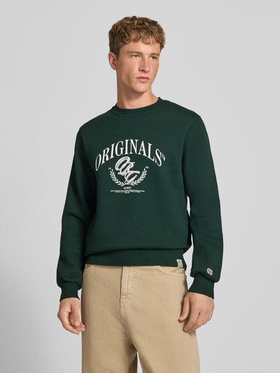Männermodel trägt dunkelgrünes Sweatshirt mit Label-Print Modell 'FREDERIKSBERG' von JACK & JONES, Baumwoll-Mix, Nahaufnahme Oberkörper.