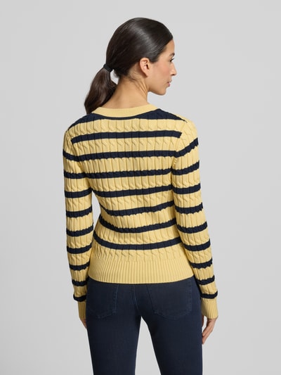 Frauenmodel trägt Slim Fit Strickpullover aus reiner Baumwolle von Tommy Hilfiger in Gelb mit dunkelblauen Streifen, Ganzkörperansicht Rückansicht.