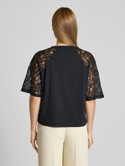 Frauenmodel trägt T-Shirt mit Spitze und Logo-Stitching von LIU JO SPORT in Schwarz, Baumwolle, Raglanärmel, Ganzkörperansicht Rückansicht.