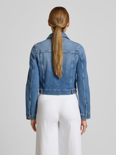 Frauenmodel trägt Jeansjacke mit Brusttaschen Modell 'NEWVICKY' von Mango, mittleres Blau, Baumwoll-Elasthan-Mix, Ganzkörperansicht Rückansicht.