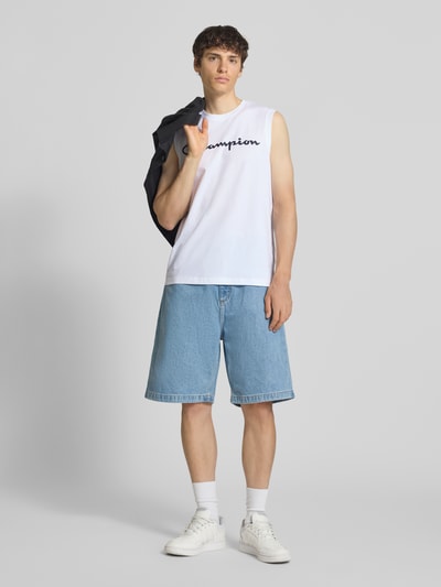 Männermodel trägt Top mit Logo und Rundhalsausschnitt von CHAMPION in Weiß, Baumwoll-Mix, Regular Fit, dezente Textur, Ganzkörperansicht von vorne.