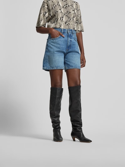 Frauenmodel trägt Jeansshorts aus reiner Baumwolle von Anine Bing in A-Linie mit 5-Pocket-Design, Knopf-Reißverschluss und Kontrast-Nähten, mittleres Blau, glatte Textur, Ganzkörperansicht von vorne.