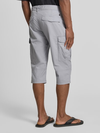 Männermodel trägt Relaxed Fit Cargoshorts aus Baumwoll-Mix von s.Oliver BLACK LABEL in Hellgrau mit Cargotaschen und Label Patch, Ganzkörperansicht Rückansicht.