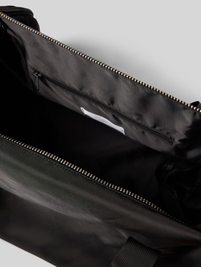 Produktfoto, schwarzer Duffel Bag mit Logo-Detail von AY STUDIOS, Reißverschlussfach innen, glatte Oberfläche, strukturierte Form.