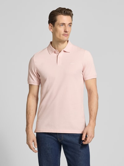 Männermodel trägt Regular Fit Poloshirt aus reiner Baumwolle von s.Oliver RED LABEL in Hellrosa, unifarben, Ganzkörperansicht von vorne.