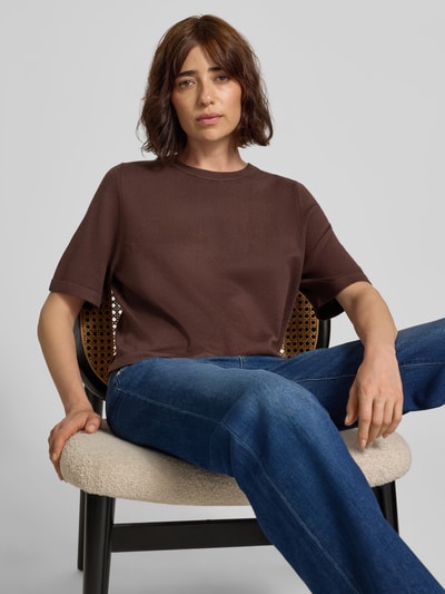 Frauenmodel trägt Boxy Fit Strickshirt aus Viskose-Mix Modell 'VMSILJE' von VERO MODA in Braun zu blauer Jeans, Nahaufnahme Oberkörper.