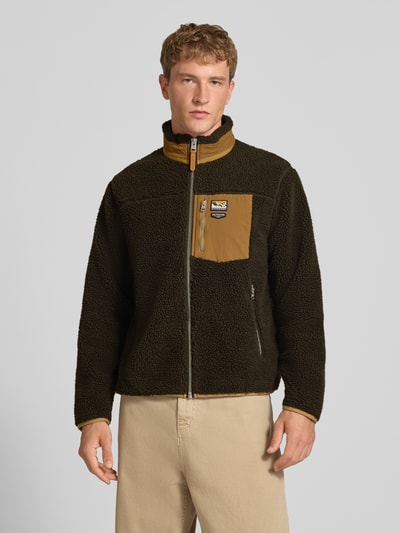 Männermodel trägt Fleecejacke mit Label-Details Modell 'MOUNTAIN' von Superdry in Braun mit Stehkragen, Teddyfell, Ganzkörperansicht von vorne.