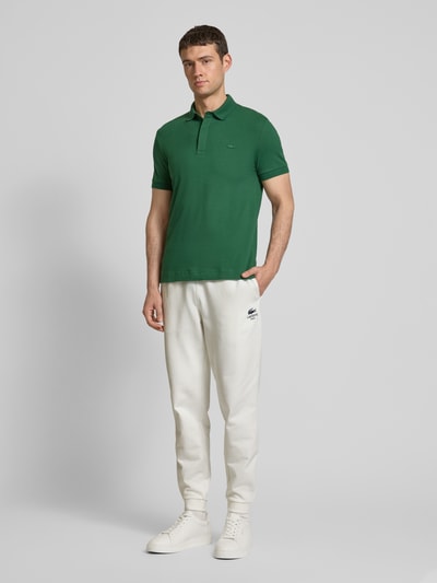 Lacoste Spodnie dresowe o kroju tapered fit z nadrukiem z logo model ‘HERITAGE’ Złamany biały 1