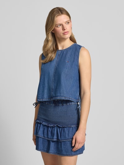 Frauenmodel trägt Relaxed Fit Denim Blusentop aus reiner Baumwolle von Tommy Jeans in Denim-Optik mit Rundhals-Ausschnitt, Cropped-Länge und Tunnelzug am Rumpfabschluss, Ganzkörperansicht von vorne.