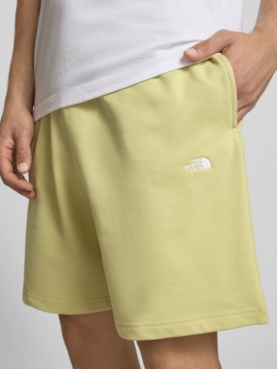 Mężczyznamodel nosi Sweatshorts mit Logo-Stitching von The North Face, bawełna, krój relaxed fit, jasny żółty, logo białe, szerokość w rozmiarze M 40 cm, długość nogawki 18 cm, zbliżenie na górną część nóg z przodu