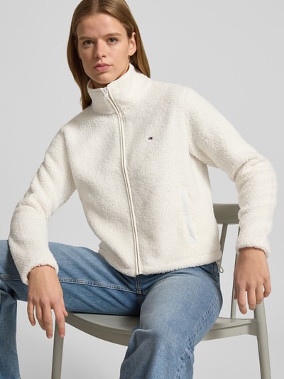 Kobiece modelka nosi Regular Fit Teddy-Jacke mit verdecktem Reißverschluss od Tommy Jeans, imitacja futerka, jednokolorowy, stójka, wyhaftowane logo, długi rękaw, kieszenie zapinane na zamek błyskawiczny, wykończenie materiału: futerko, Ganzkörperansicht von vorne.