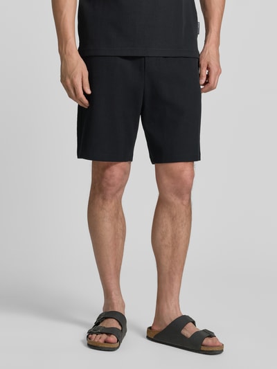 Męski model nosi Relaxed Fit Sweatshorts aus reiner Baumwolle od Tom Tailor Denim, efekt: jednolity kolor, prążkowana dzianina, wpuszczane kieszenie boczne, kieszeń z tyłu, materiał: bawełna, szorty z elastycznym pasem, widok całej sylwetki z przodu.