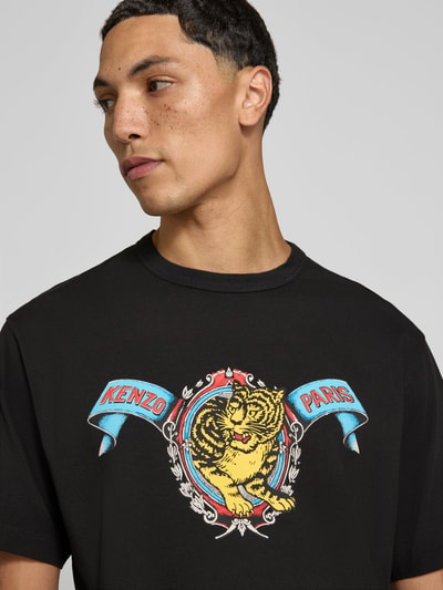 Männermodel draagt Regular Fit T-Shirt aus reiner Baumwolle van Kenzo met labelprint op zwarte stof met ronde hals, Nahaufnahme Oberkörper, Heren t-shirt van puur katoen, regular fit, ronde hals, labelprint, met korte mouwen, ruglengte bij maat M: 69 cm.