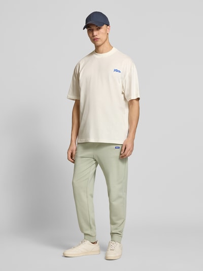 Männermodel trägt Relaxed Fit Sweatpants aus reiner Baumwolle Modell 'NAPIN' von Hugo Blue in Optik: Unifarben, Materialverarbeitung: Sweat, Label-Patch, Tunnelzug, Bundabschluss: elastisch, Beinabschluss: gerippt, seitliche Eingrifftaschen, Farbe Hellgrün, Ganzkörperansicht von vorne.