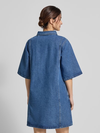 Frauenmodel trägt Jeanskleid mit Brusttaschen Modell 'Mola' von LOLLYS LAUNDRY, Baumwoll-Viskose-Mix, Gerader-Schnitt, Minikleid, Ganzkörperansicht Rückansicht.