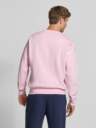 Männermodel trägt Relaxed Fit Sweatshirt aus Baumwoll-Mix von Nike in Hellrosa mit glatter Oberfläche, Ganzkörperansicht Rückansicht. Herren Sweatshirt von Nike.
