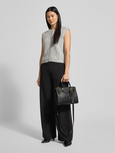 Frauenmodel trägt schwarze Handtasche mit Label-Applikation Modell 'SATCHEL MANHATTAN' von Liu Jo White, Hauptfach mit Reißverschluss, Tragehenkel, abnehmbarer Schulterriemen, Maße 27x20x13 cm, Länge Schulterriemen 117 cm; Ganzkörperansicht von vorne.