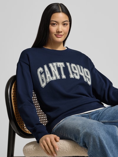 Frauenmodel trägt Sweatshirt mit Label-Print und Rundhalsausschnitt von Gant, Reine Baumwolle, Relaxed-Fit, Dunkelblau, Nahaufnahme Oberkörper.
