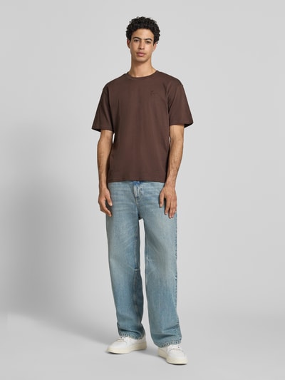 Męski model nosi Regular Fit T-Shirt mit Logo-Stitching von KARL KANI z bawełny, okrągły dekolt, długość tyłu w rozmiarze M: 64 cm, Ganzkörperansicht von vorne.