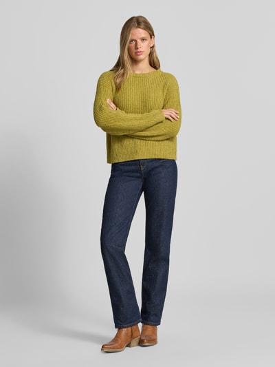 Frauenmodel trägt Relaxed Fit Strickpullover mit elastischen Abschlüssen von REVIEW in Gelb, blaue Jeans, strukturierte Oberfläche, Ganzkörperansicht von vorne. Lockere Passform, Rundhalsausschnitt, Rücklänge 54 cm, Ärmellänge 58 cm.