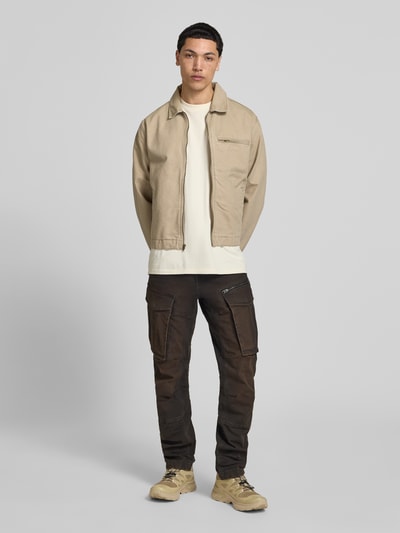 Männermodel trägt Regular Tapered Fit Hose mit Cargotaschen Modell 'Rovic' von G-Star Raw in Braun, Baumwoll-Elasthan-Mix, Used-Look, Ganzkörperansicht von vorne.
