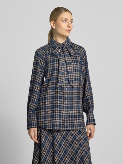 Frauenmodel trägt Regular Fit Hemdbluse aus Viskose-Mix von Oui, kariertes Muster in Blau-Beige, Zierschleife, Ganzkörperansicht von vorne.