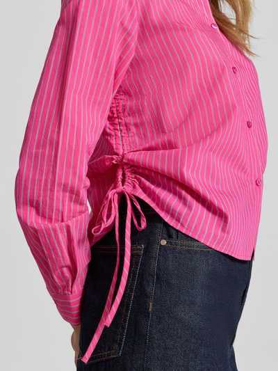 Frauenmodel trägt Hemdbluse mit seitlichen Schnürungen und Hemdblusenkragen von Smith and Soul im Baumwoll-Mix, Regular-Fit, Knopfleiste, Sportmanschetten, Rückenlänge 56 cm, Ärmellänge 59 cm; rosa mit weißen Streifen, strukturierte Oberfläche, Nahaufnahme Oberkörper.