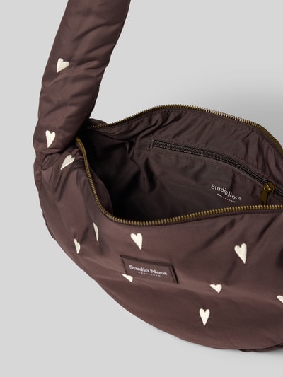 Produktfoto, Shoulder Bag mit Logo-Detail von Studio Noos in Dunkelbraun mit weißem Allover-Herz-Motiv-Stitching, Reißverschluss, sichtbares Innenfach, Breite 38 cm, Länge 20 cm, Tiefe 8 cm, Schulterriemen 88 cm, Stoff mit glatter Textur