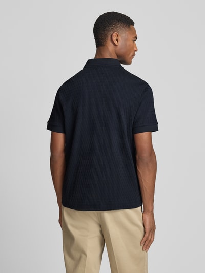 Męski model nosi Regular Fit Poloshirt mit V-Ausschnitt Modell 'Rauljose' von JOOP! Collection z czarnej bawełny z fakturowanym wzorem, długość tyłu w rozmiarze M: 69 cm, ganzkörperansicht rückansicht.