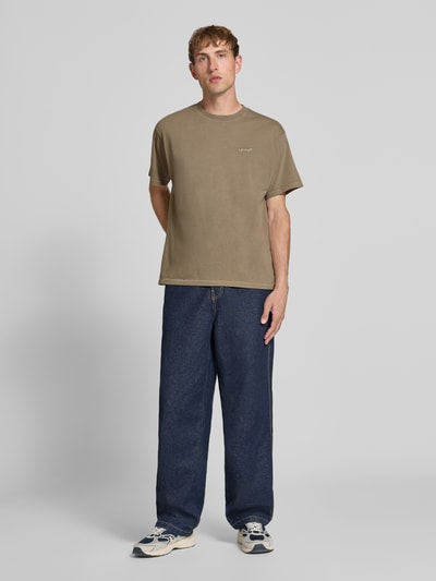 Männermodel trägt Relaxed Fit T-Shirt aus reiner Baumwolle Modell 'VINTAGE TEE' von Levi's®, Herren T-Shirt, olive, Jeans, Sneaker, Ganzkörperansicht von vorne.