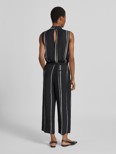 Vrouwenmodel draagt zwarte Jumpsuit uit viscose-mix in allover-look model 'Cafalli' van someday, regular fit, rugaanzicht Ganzkörperansicht Rückansicht.