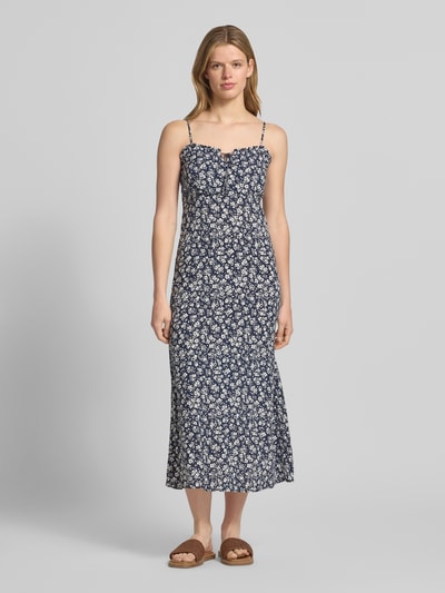 Modelka kobieca ma na sobie Schmales Freizeitkleid aus reiner Viskose Modell 'NELLY' od Only, wzór animal print, długość midi, Henley, cienkie ramiączka, popelina, kolor granatowy z białym nadrukiem, krój slim fit, widok całej sylwetki z przodu.