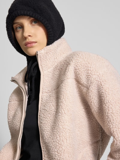 Kobiece modelka nosi Regular Fit Teddyjacke mit Stehkragen Modell 'SADIA' od Pieces, beżowy teddyfell, jednokolorowy styl, krój regular fit, długi rękaw, zapinana na zamek, boczne kieszenie, zbliżenie górnej części ciała.