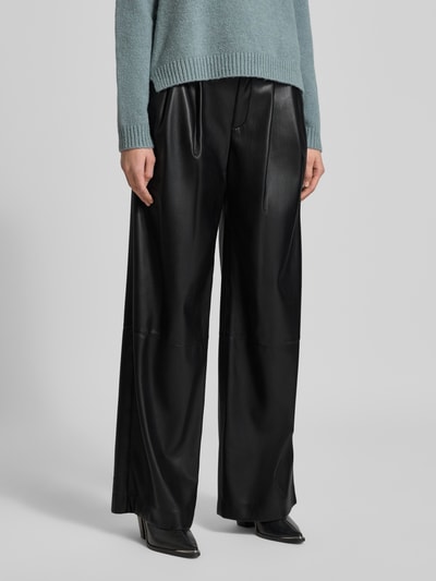Frauenmodel trägt Relaxed Fit Weite Hose mit Bundfalten Modell 'TADESA' von BOSS in glänzender Optik aus Kunstleder, Nahaufnahme Unterkörper.