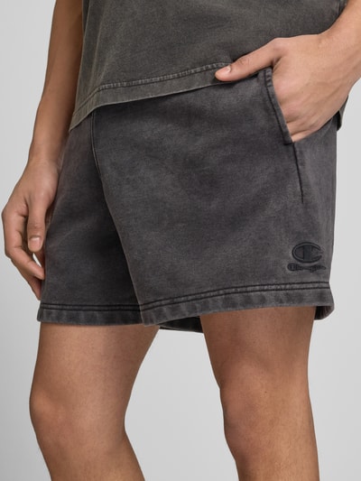 Männermodel trägt Sweatshorts mit Eingrifftaschen von CHAMPION in Dunkelgrau, Baumwoll-Mix, Label-Stitching, Nahaufnahme Oberschenkel.