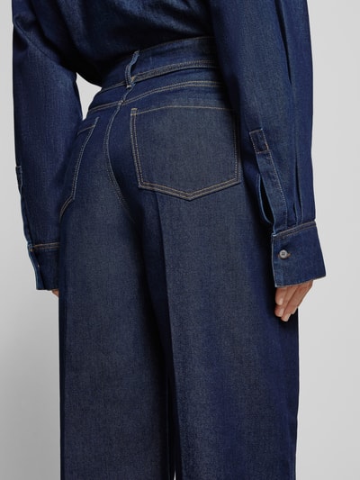 Vrouwenmodel draagt Wide Leg Jeans mit Bindegürtel van Christian Berg Woman, donkerblauw met lengtenaden, detailopname rug.