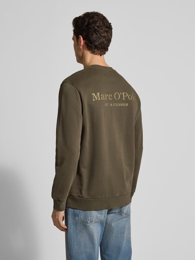 Männermodel trägt Regular Fit Sweatjacke aus reiner Baumwolle von Marc O'Polo in Olivgrün, unifarben, Label Print, Ganzkörperansicht Rückansicht.