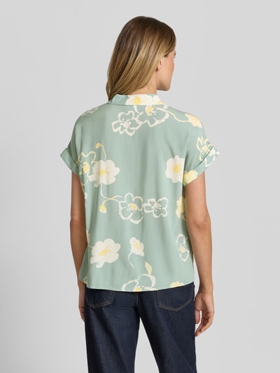 Vrouwenmodel draagt Bluse aus Viskose mit fixiertem Ärmelaufschlag van JAKE*S STUDIO WOMAN, zachtgroen met witte en gele bloemenprint, recht model met kentkraag, knoopsluiting, mouwen met vaste mouwomslag, ruglengte 62 cm bij maat 36, mouwlengte 13 cm bij maat 36, geheel van viscose, geheel van achteren.