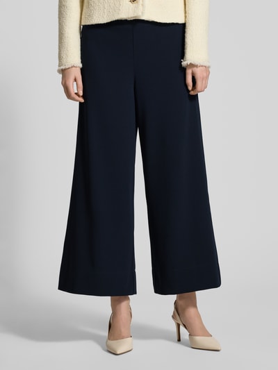 Frauenmodel trägt Stoffhose in verkürzter Passform Modell 'Coralie' von MAC, dunkelblau, lockerer Schnitt, Nahaufnahme Unterkörper. Material-Mix mit Stretch, elastischer Bund, Nahtreißverschlusstaschen.