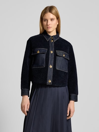Frauenmodel trägt Bouclè-Jacke mit Kentkragen und Brusttaschen von LUISA CERANO in Dunkelblau, Gerader-Schnitt, Nahaufnahme Oberkörper. Rückenlänge 58 cm, Schulterbreite 42 cm, Brustweite 52 cm, Ärmellänge 57 cm bei Größe 36.